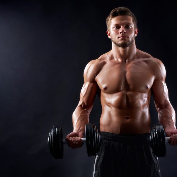 He is a winner. Horizontal studio shot of a handsome shirtless muscular man working out with heavy dumbbells
