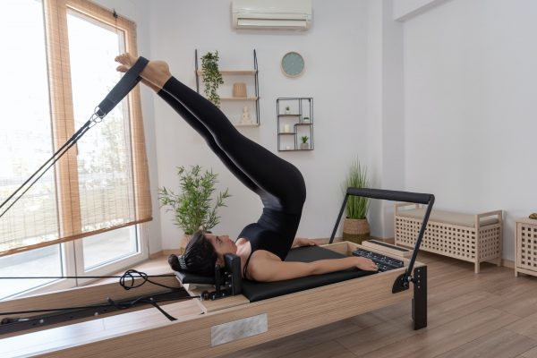 young-woman-exercising-on-pilates-reformer-bed.jpg